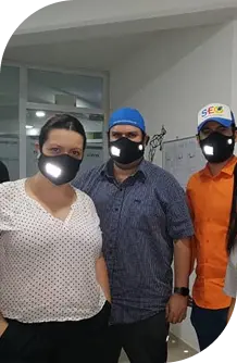Grupo de personas con mascarillas iluminadas en un entorno de trabajo, reflejando medidas de salud y seguridad.
