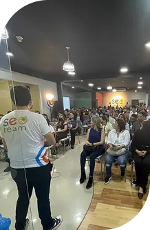 Asistente en un evento de SEO hablando ante una multitud en un ambiente profesional.